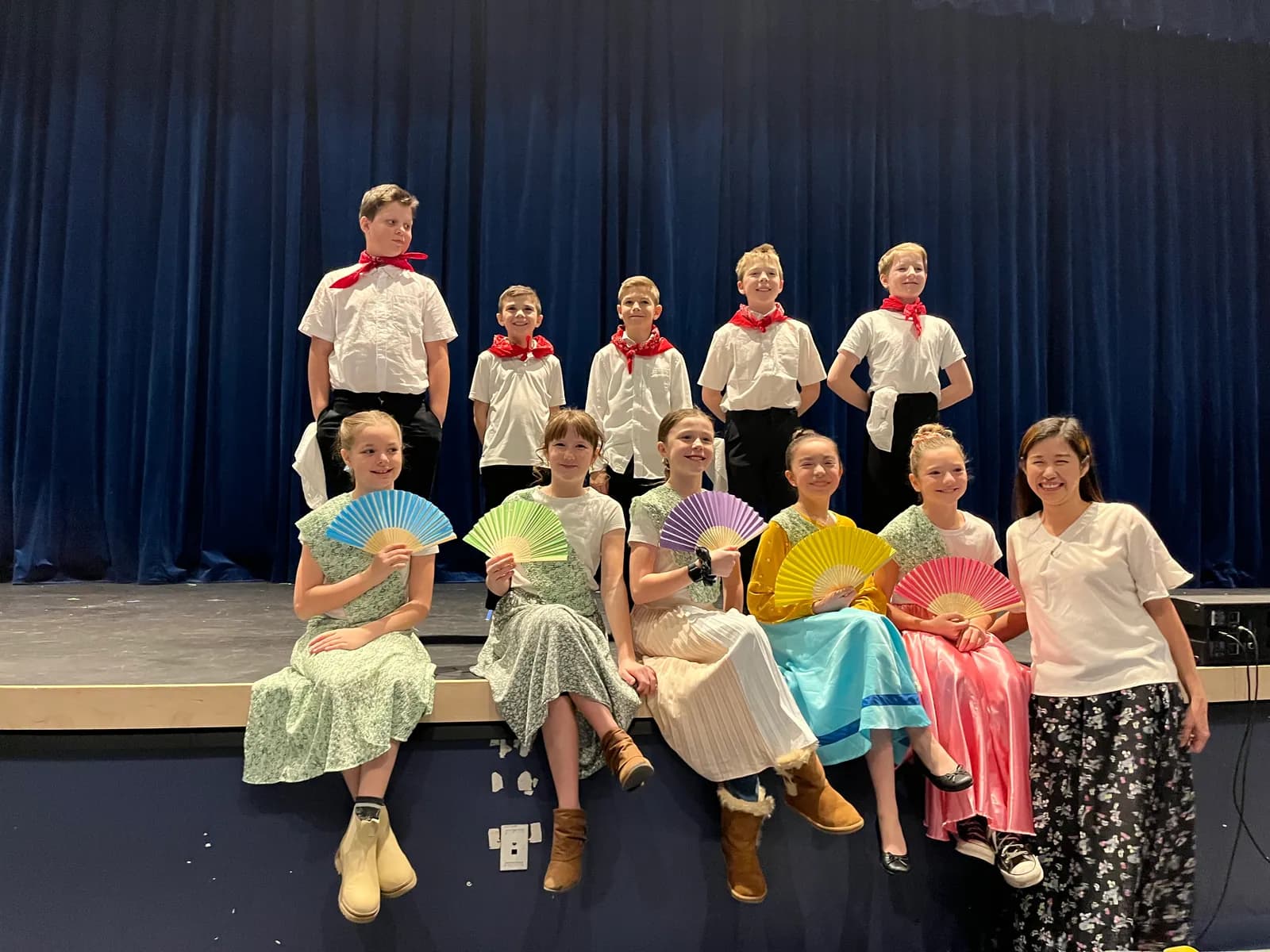 Elementary students in costume on stage with their teacher