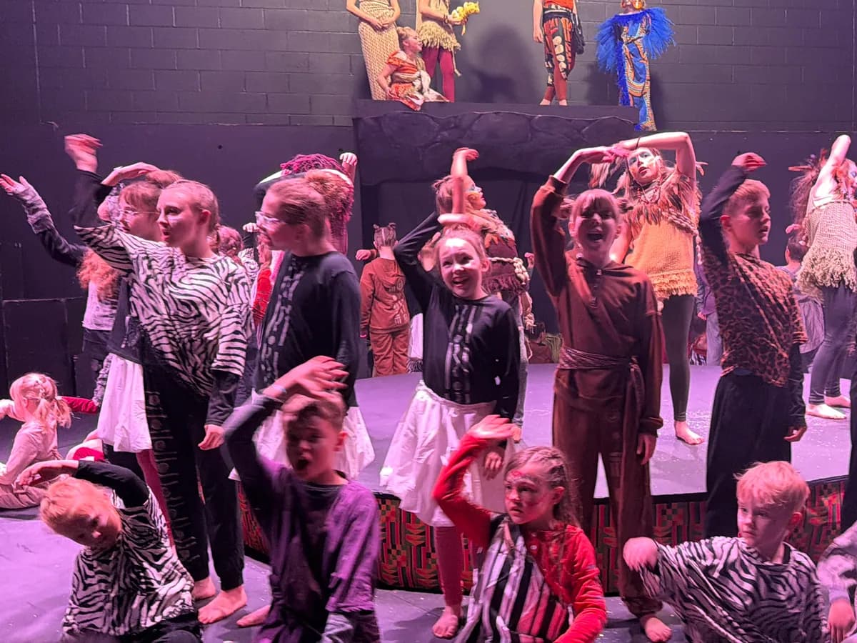 Students in animal costumes performing under stage lights